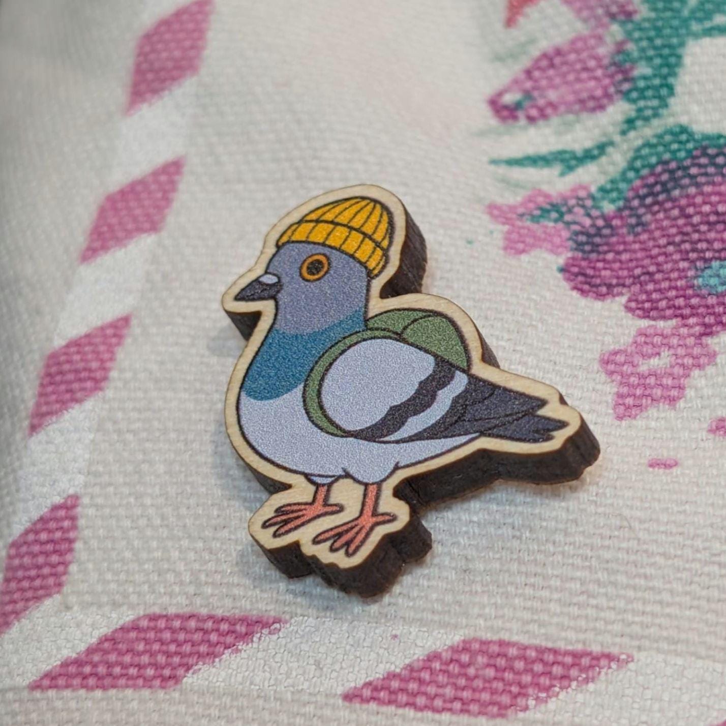 Wooden pigeon pin with a yellow beanie on a textured fabric background