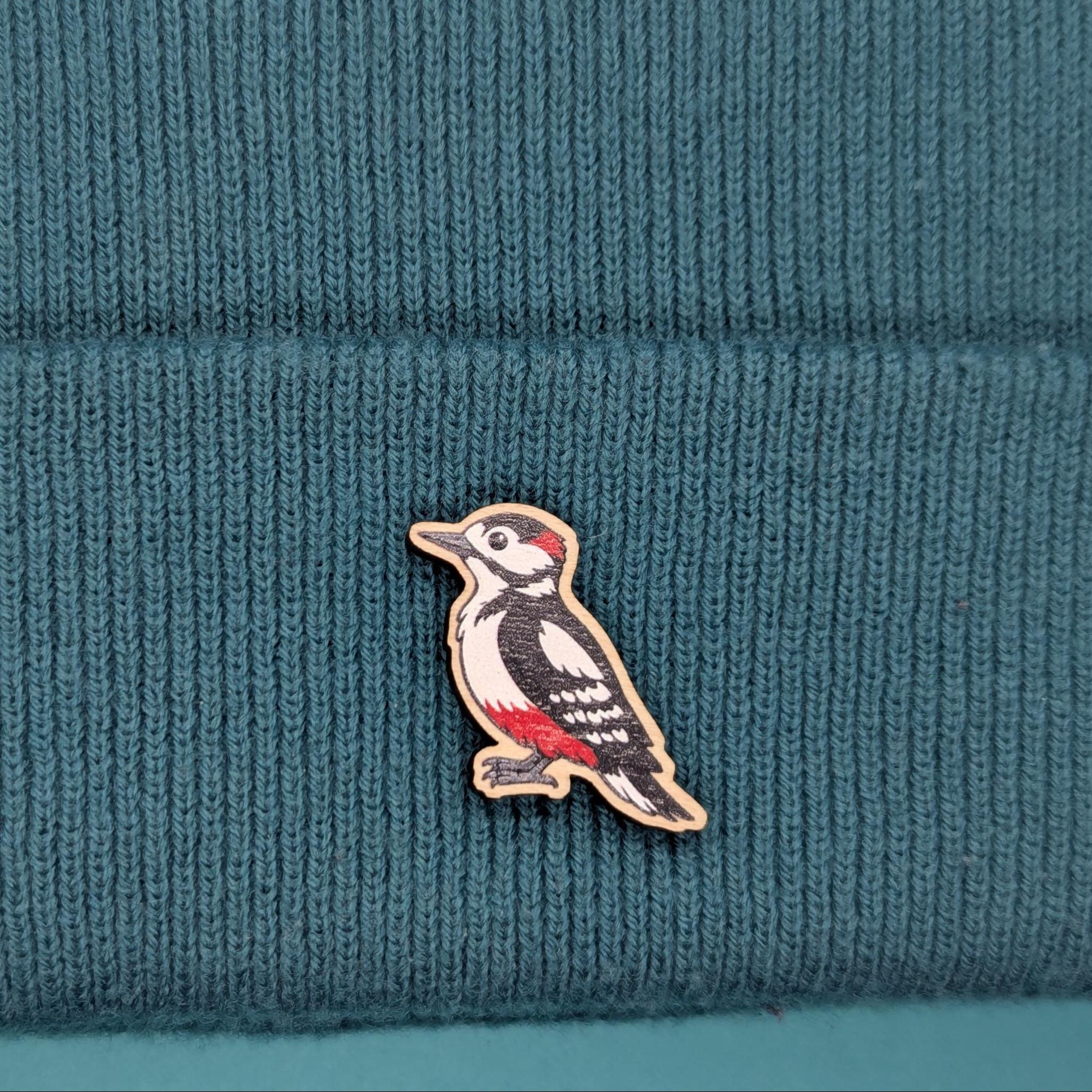 Woodpecker wooden pin on a teal knitted fabric background