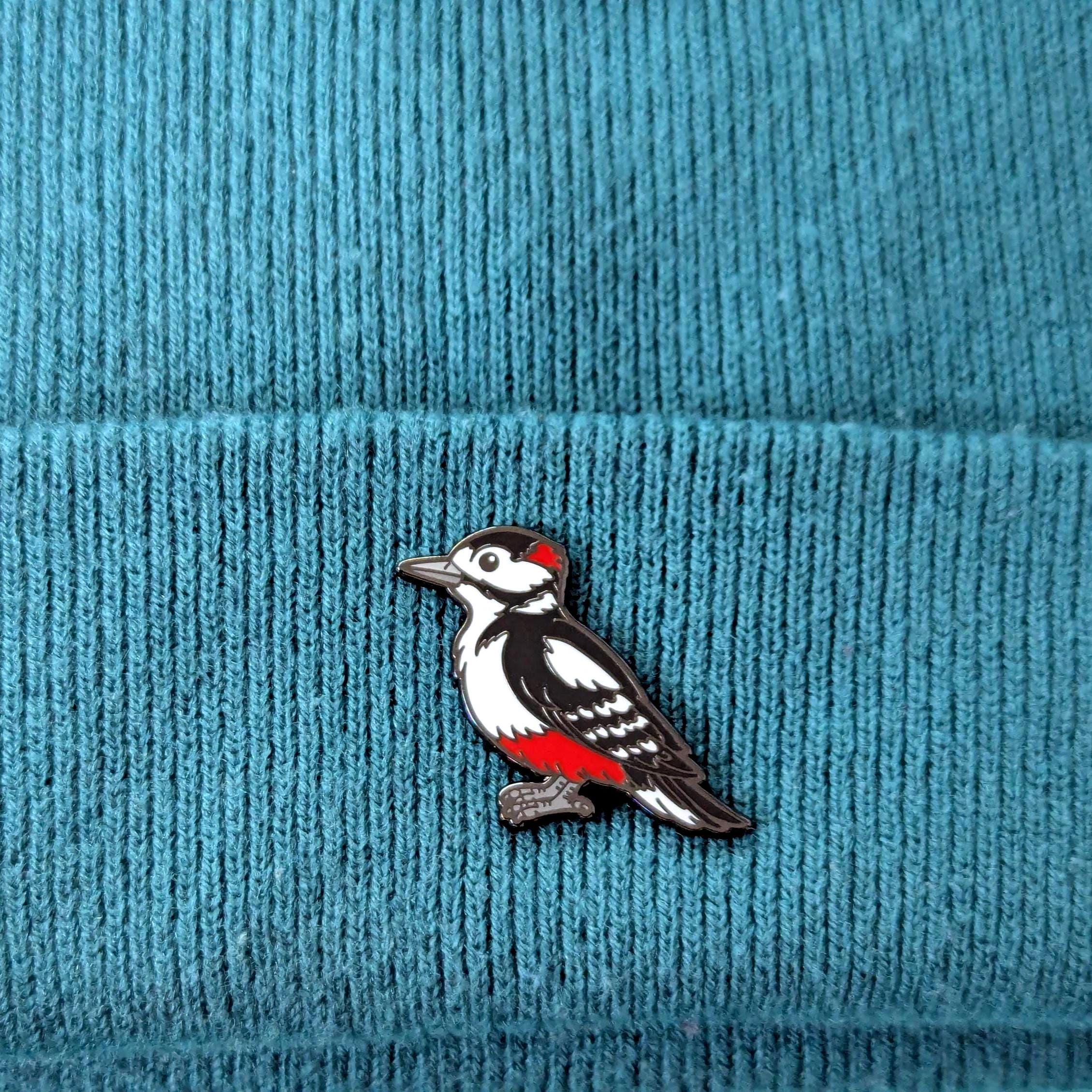 great spotted woodpecker pin on a blue textured fabric background
