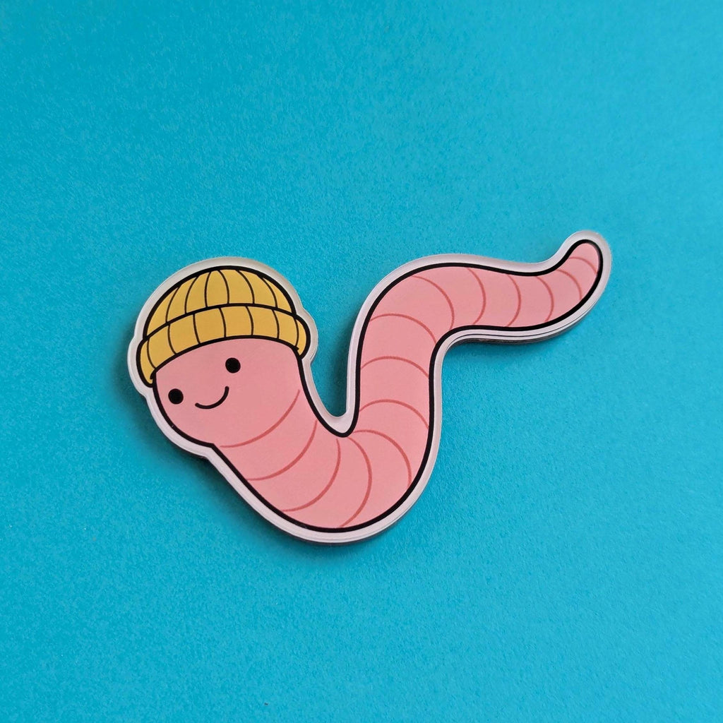 Fridge magnet of a cartoon worm wearing a yellow beanie on a blue background