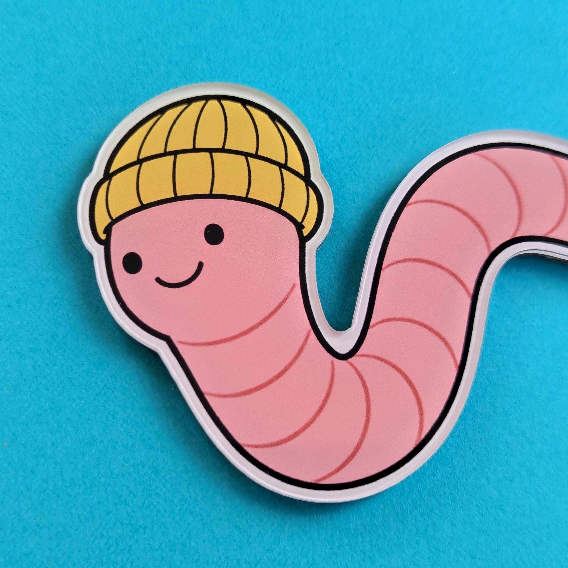Close up of fridge magnet with a worm wearing a yellow beanie on a blue background