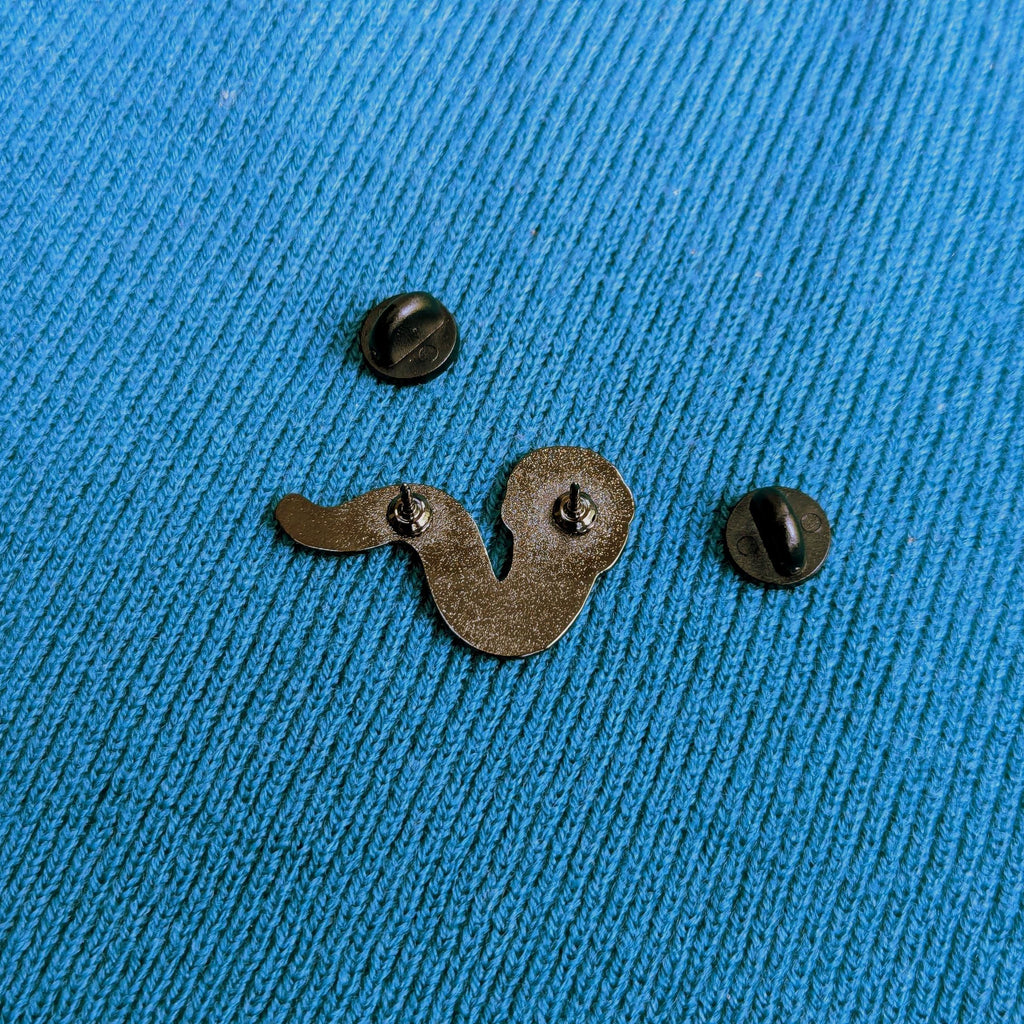 Back of worm enamel pin badge on a blue textured fabric background