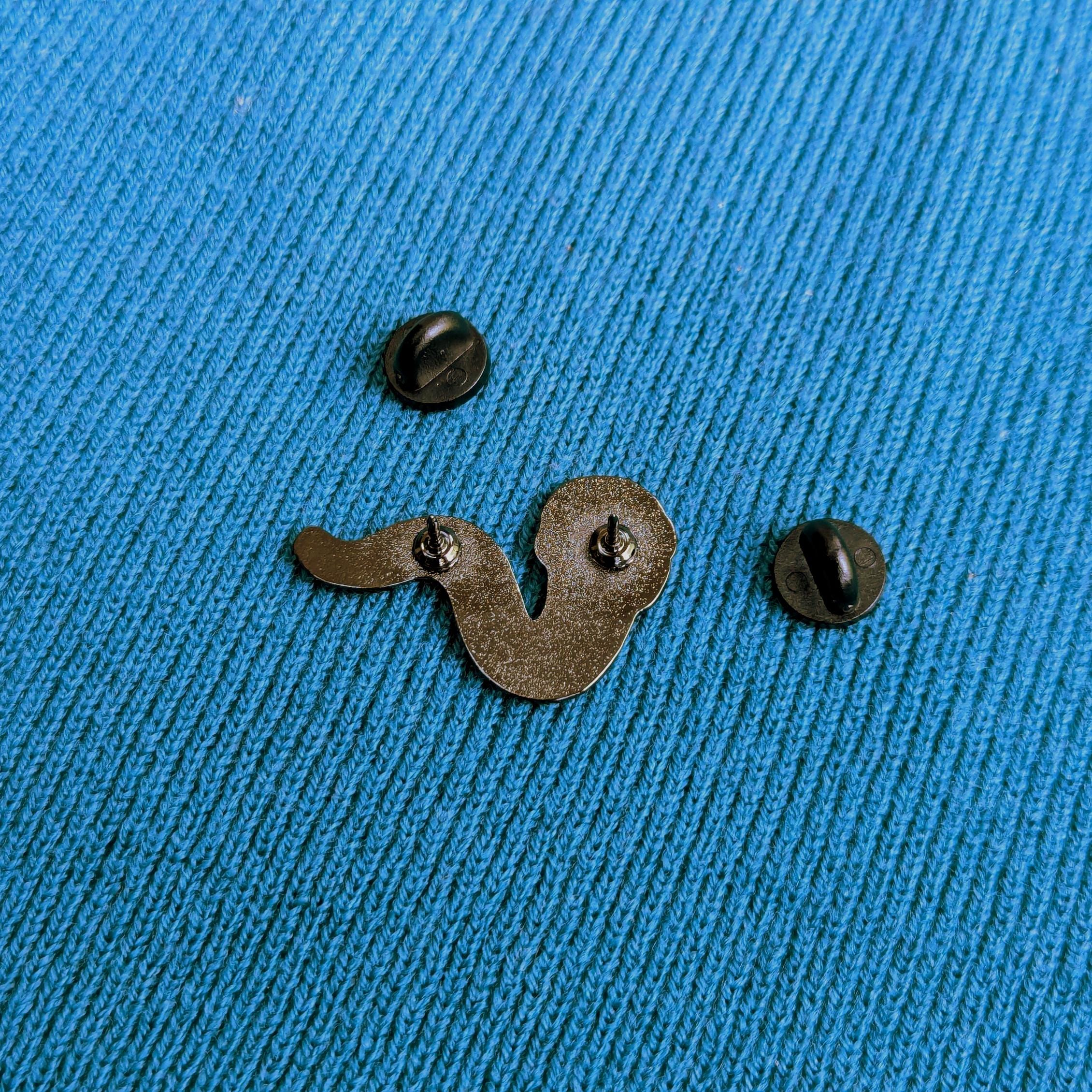 Back of worm enamel pin badge on a blue textured fabric background