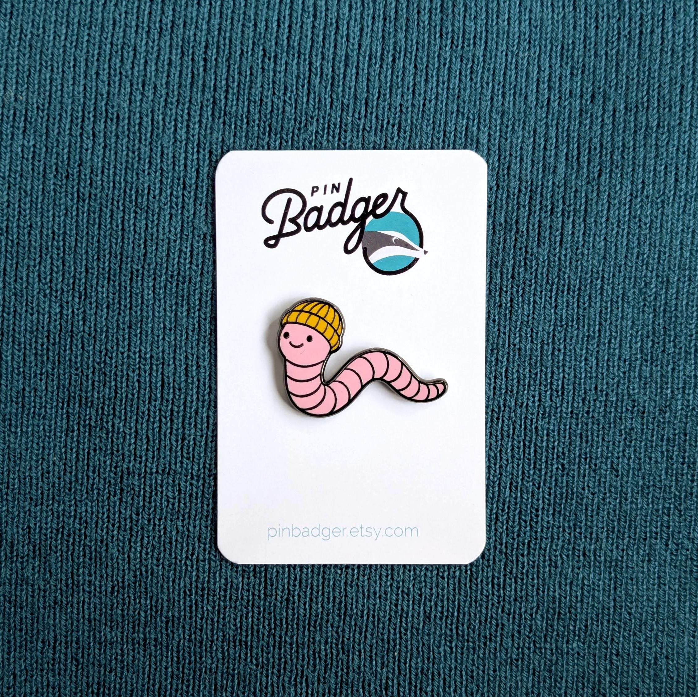 Pin Badger worm pin on a white card against a teal background