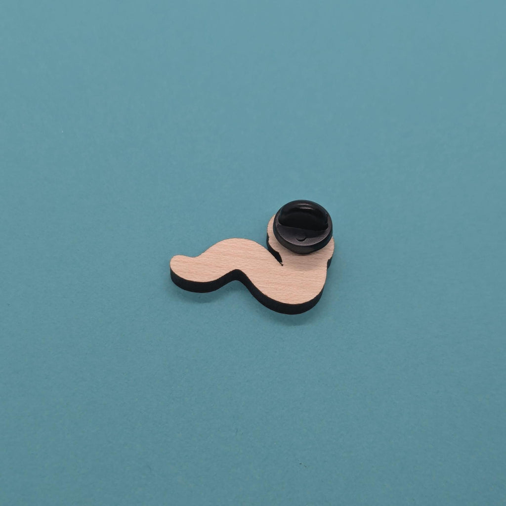 Wavy worm wooden pin badge back with black cap on a teal background