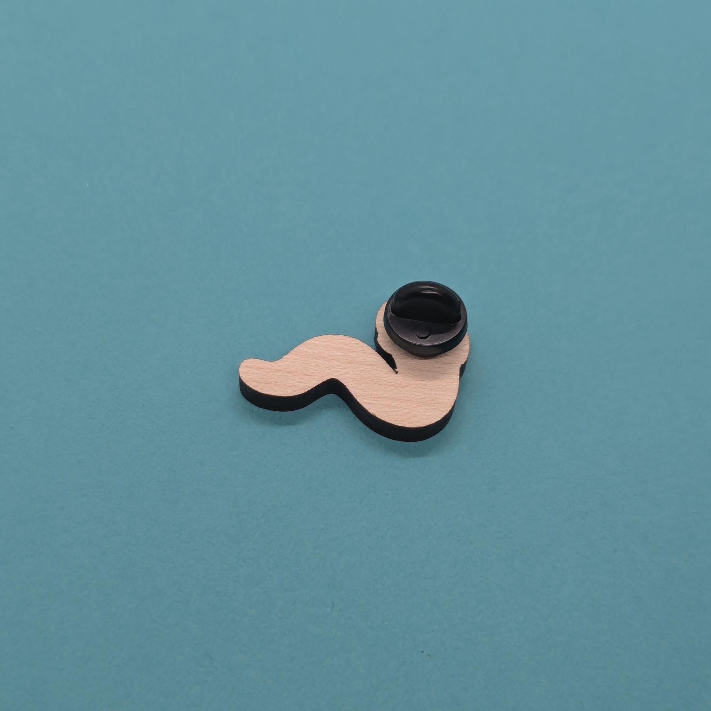 Wavy worm wooden pin badge back with black cap on a teal background